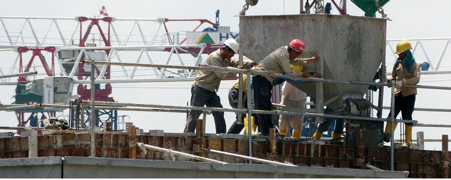 workers pushing heavy construction equipment